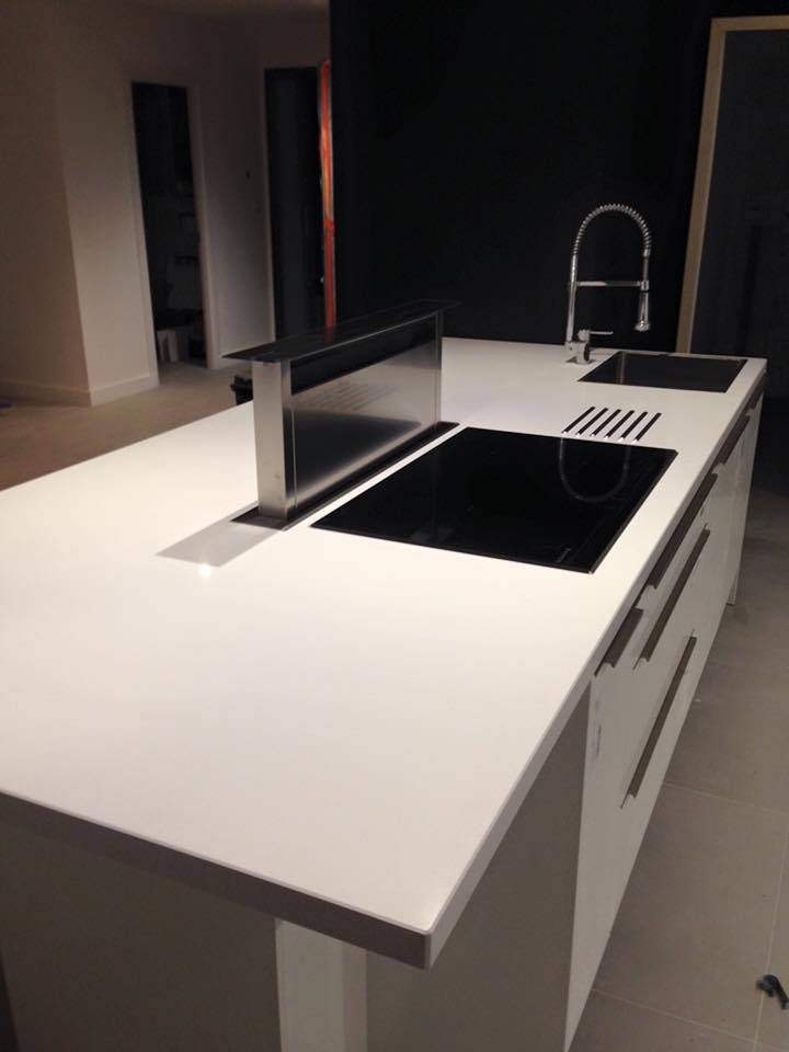 Création d'une cuisine blanche laquée avec îlot cuisson central et hotte encastrable dans le plan de travail à Beaulieu