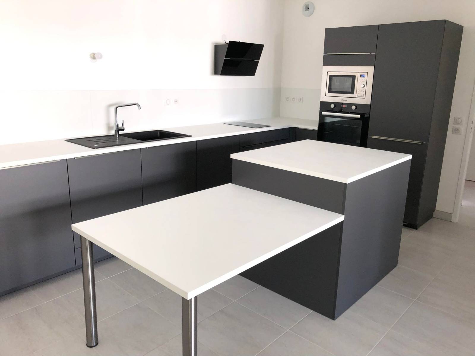 Cuisine aménagée, façades gris anthracite mat, avec des poignées intégrées, un plan de travail bois stratifié blanc en 29mm