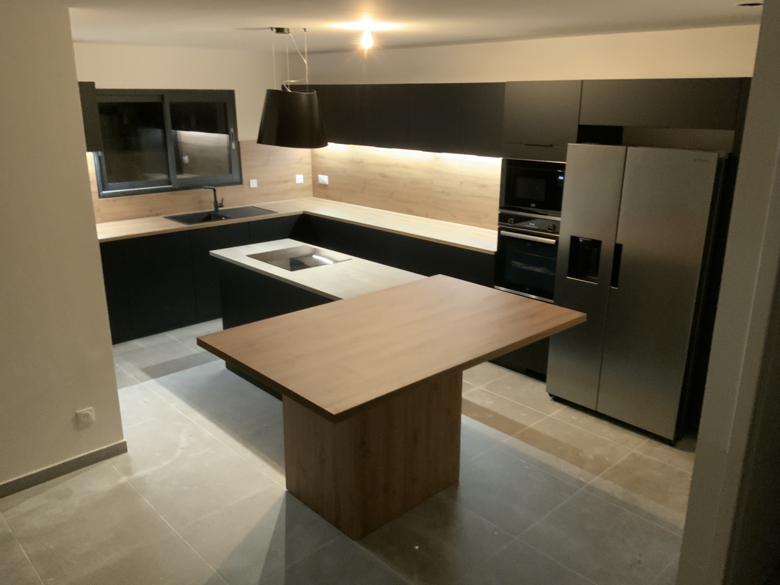 Création d'une cuisine en U noire mate avec plans bois, îlot central et coin snack à Saint-Gély-du-Fesc