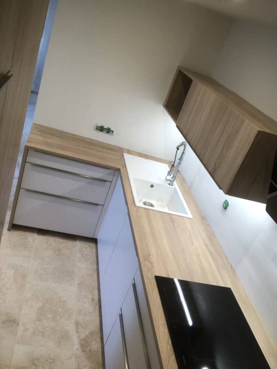 Montage d'une cuisine façade laquée blanc à Beaulieu (34) : poignée profilé alu, plan de travail bois noyer.