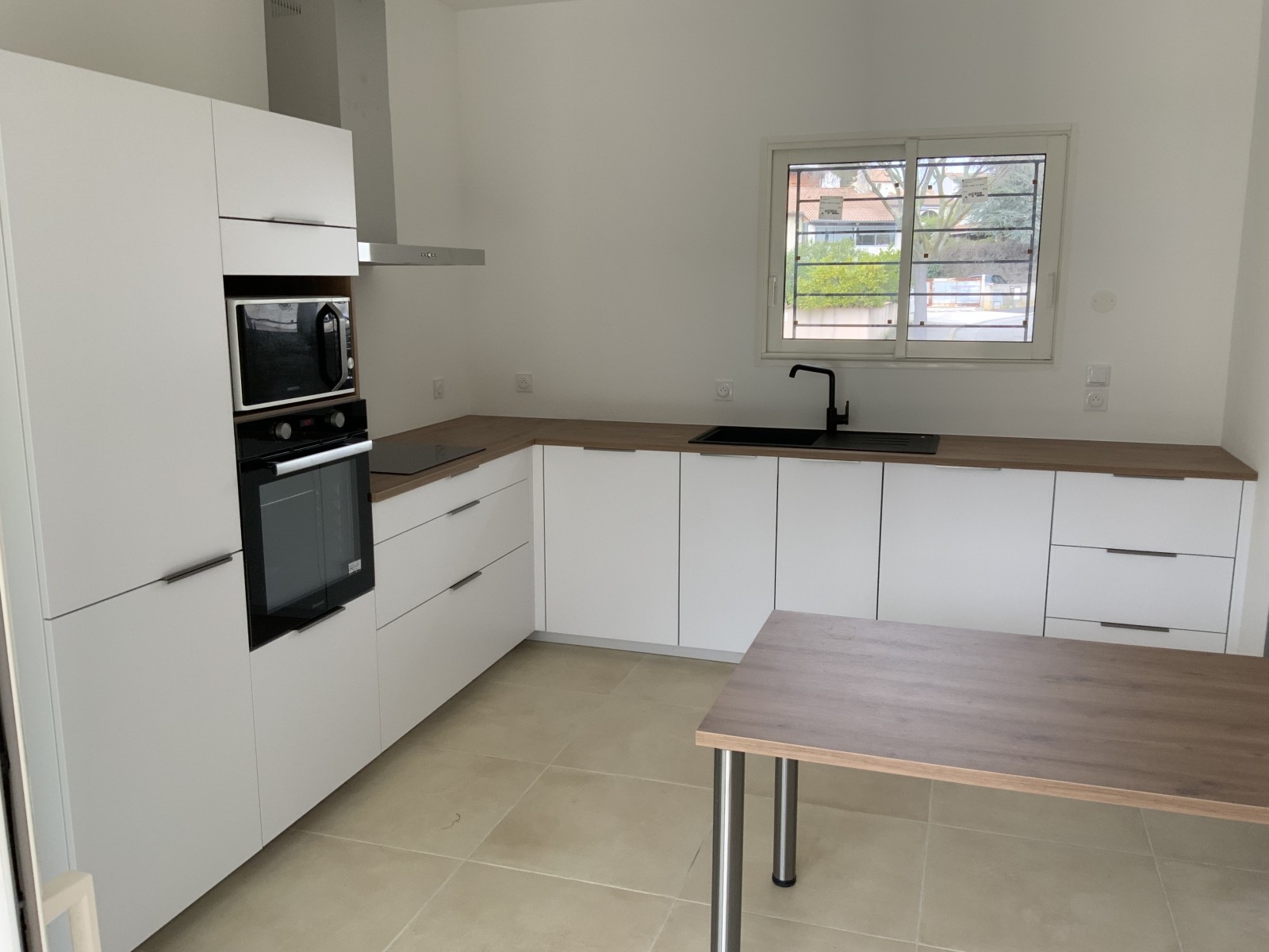 Cuisine en L sur mesure blanche mate avec plan bois et table intégrée en îlot indépendant à Saint-Gély-du-Fesc