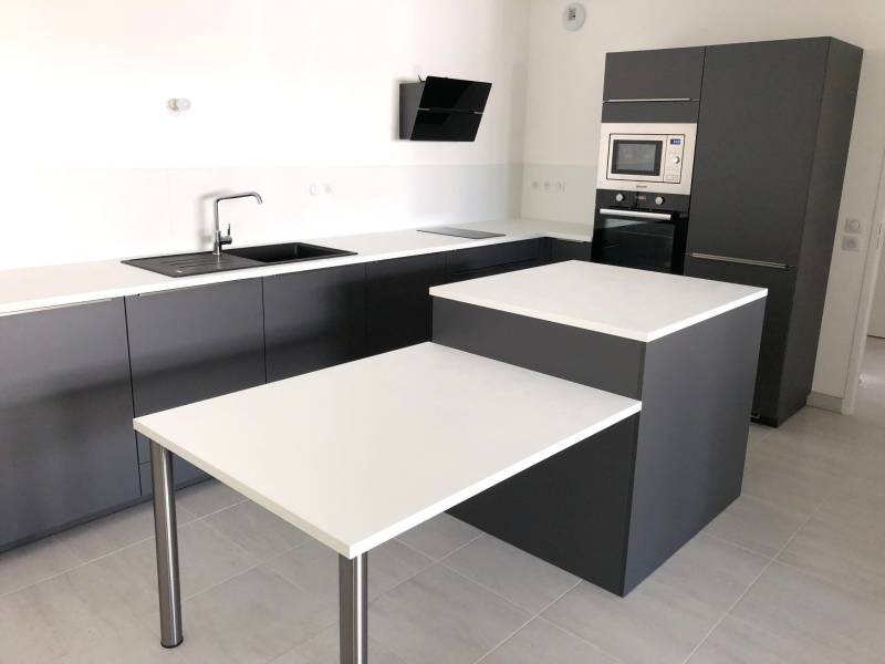 Cuisine aménagée, façades gris anthracite mat, avec des poignées intégrées, un plan de travail bois stratifié blanc en 29mm