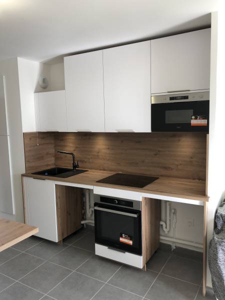 Cuisine aménagée élégante et fonctionnelle lumineuse et chaleureuse par ses tons clairs blanc brillant et bois